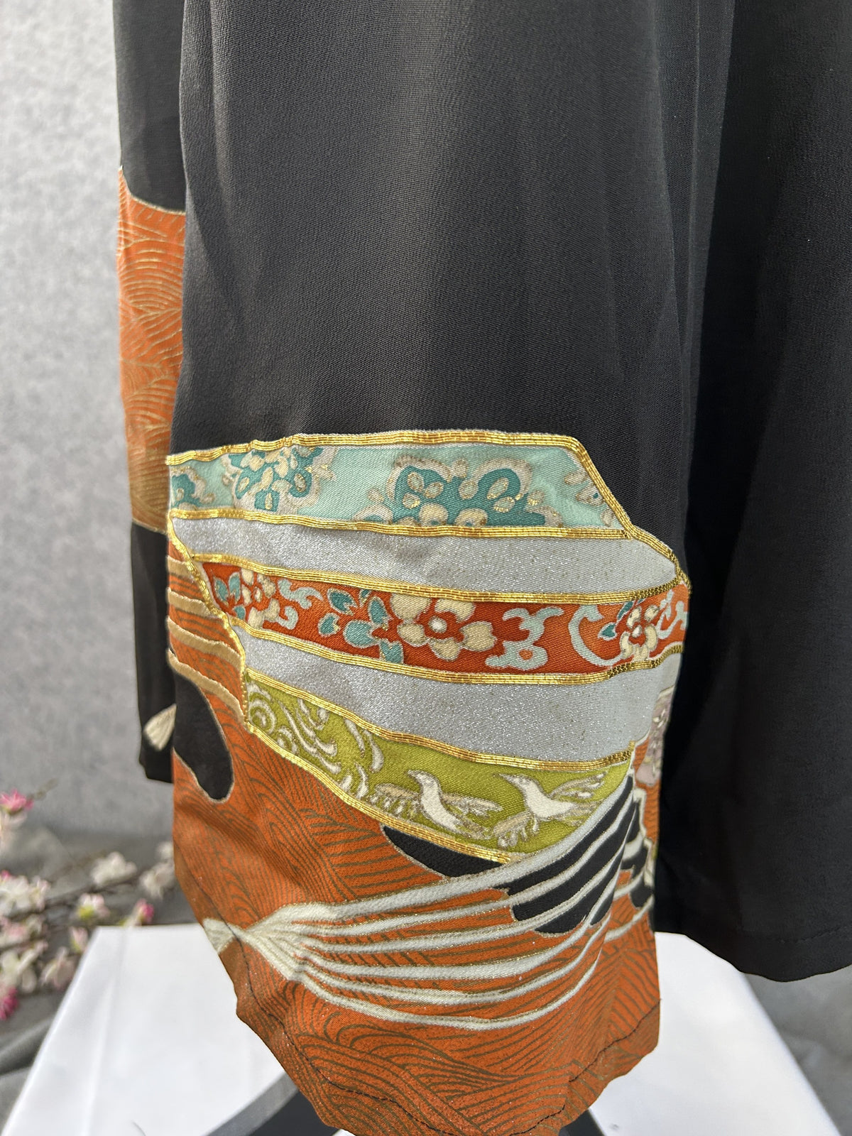 Hem detail with teal, silver and red bands and white crane on black silk