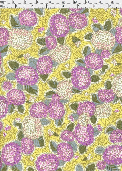 Chiyogami paper with Floral pattern with purple flowers and green leaves on a yellow background with a ruler for scale