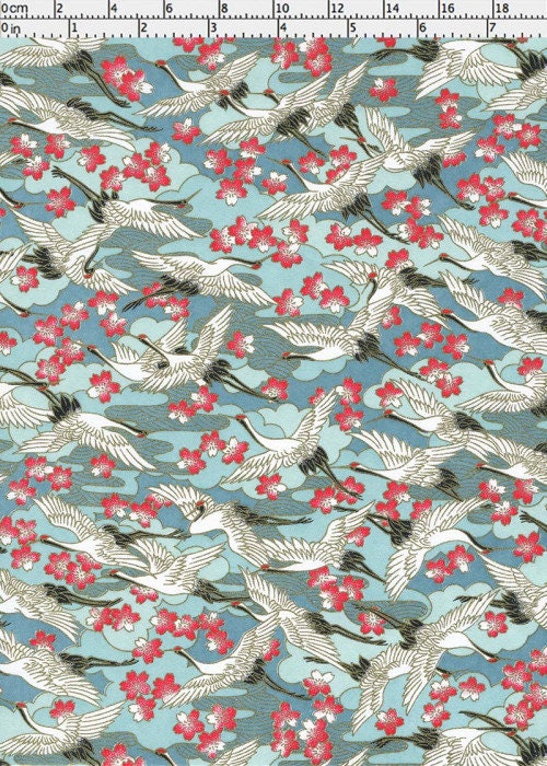 Chiyogami paper with pattern of white birds and red flowers on a blue background with a ruler for scale