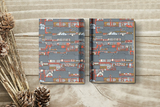 Two patterned books made with chiyogami paper in a bookbinding project on a wooden surface with decorative elements.