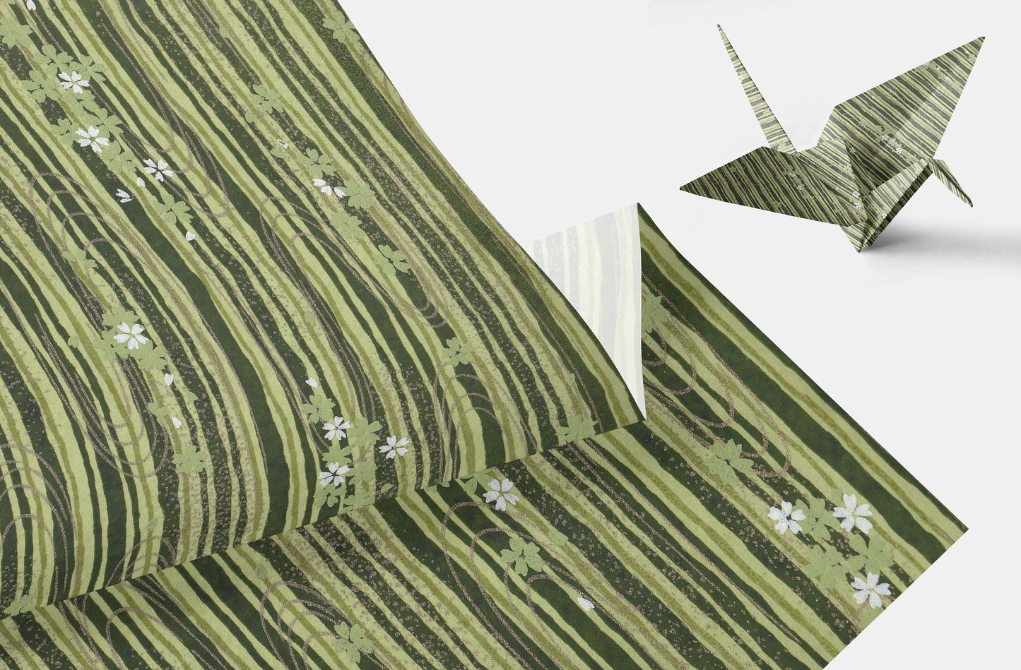 Green chiyogami paper with floral patterns and a folded paper crane on a white background