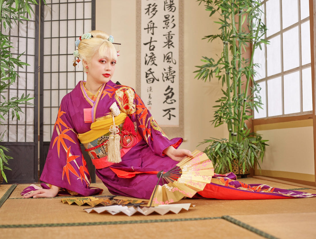Model in a purple furisode with long sleeves and gold fans, sitting on tatami in a Japanese room