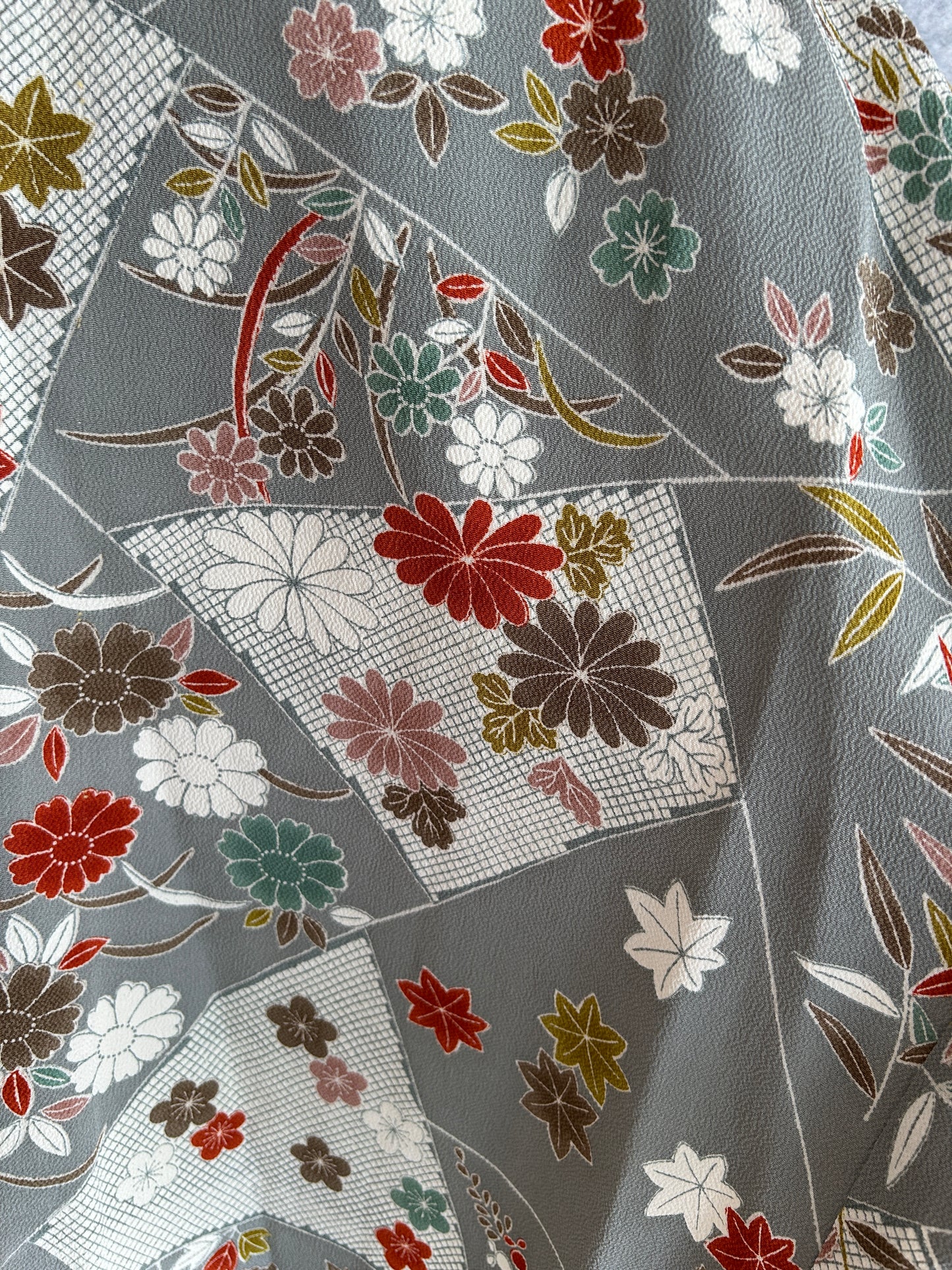 Close-up of floral fabric pattern with red, green, and white flowers on a gray background