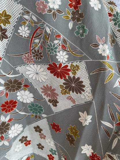 Close-up of floral fabric pattern with red, green, and white flowers on a gray background