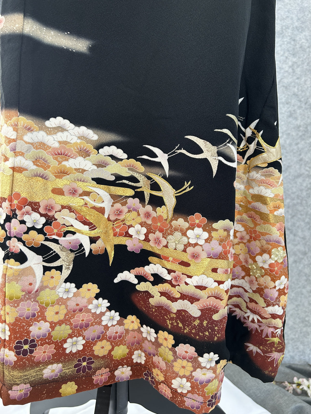 Close-up of gold and white cranes over pink and orange blossoms