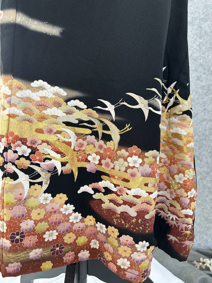Close-up of gold and white cranes over pink and orange blossoms