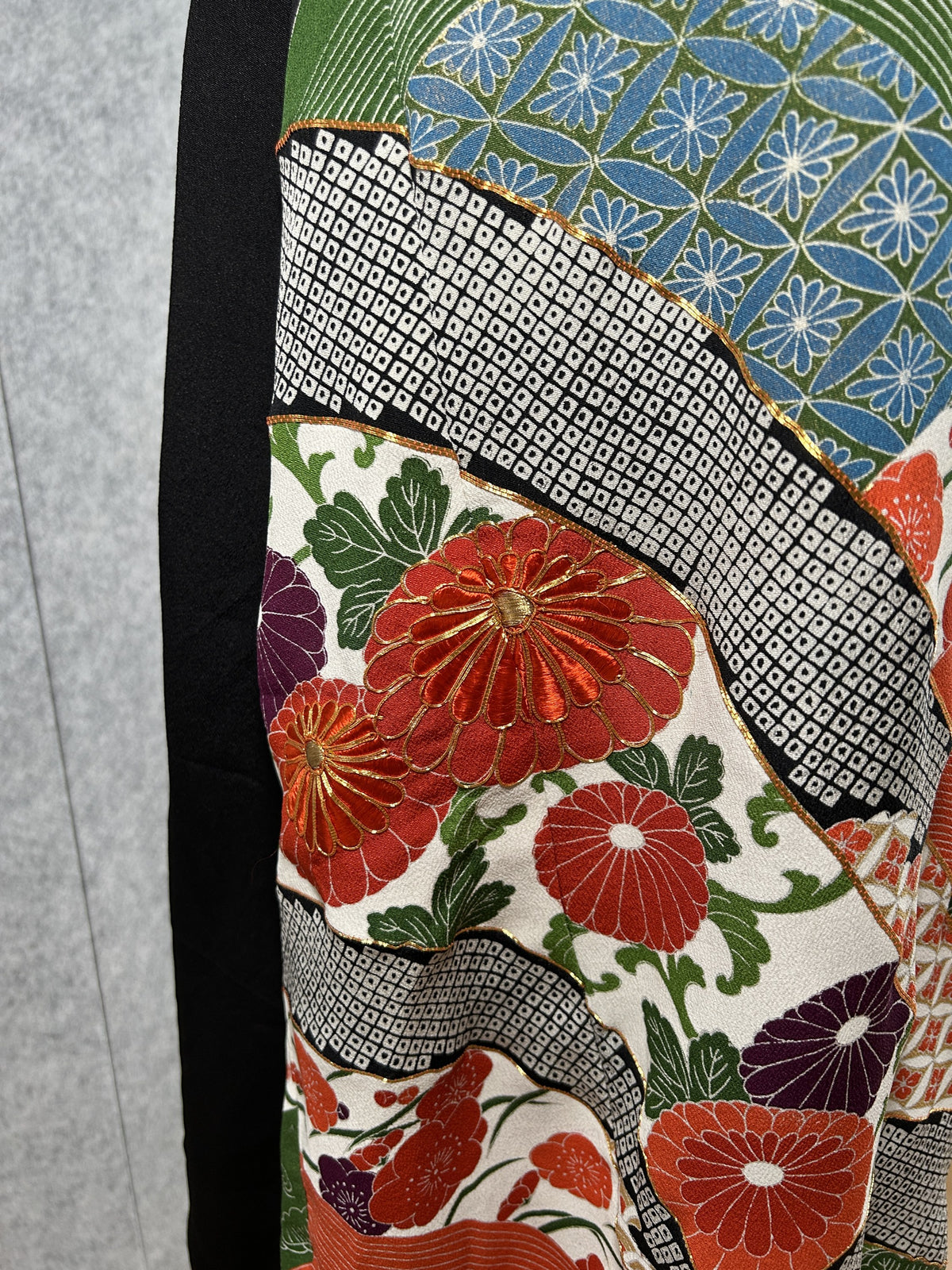 Close-up of chrysanthemums and blue flower pattern with gold outlines on black dress