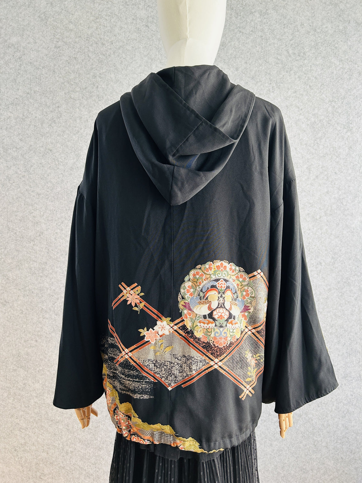 Black kimono hoodie with hood and medallion motif on the lower back, back view
