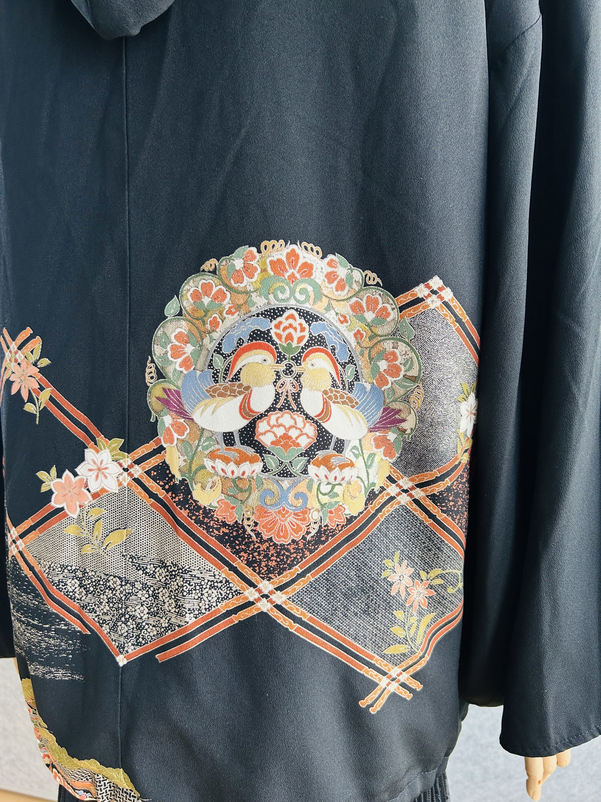 Back of black kimono hoodie, close-up of duck medallion and lattice pattern