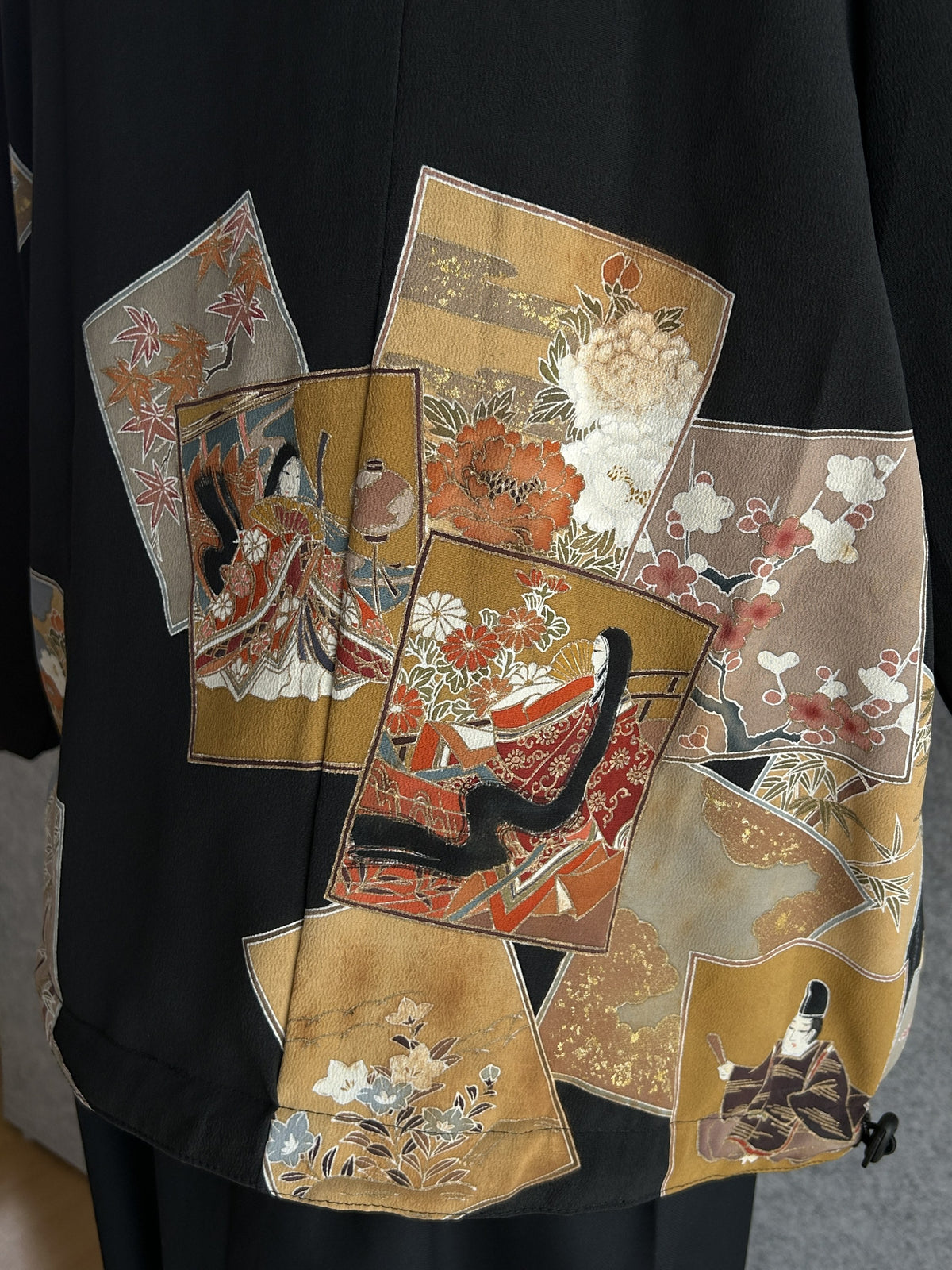 Black high collar kimono jacket, detail of robed figures and flowers on back