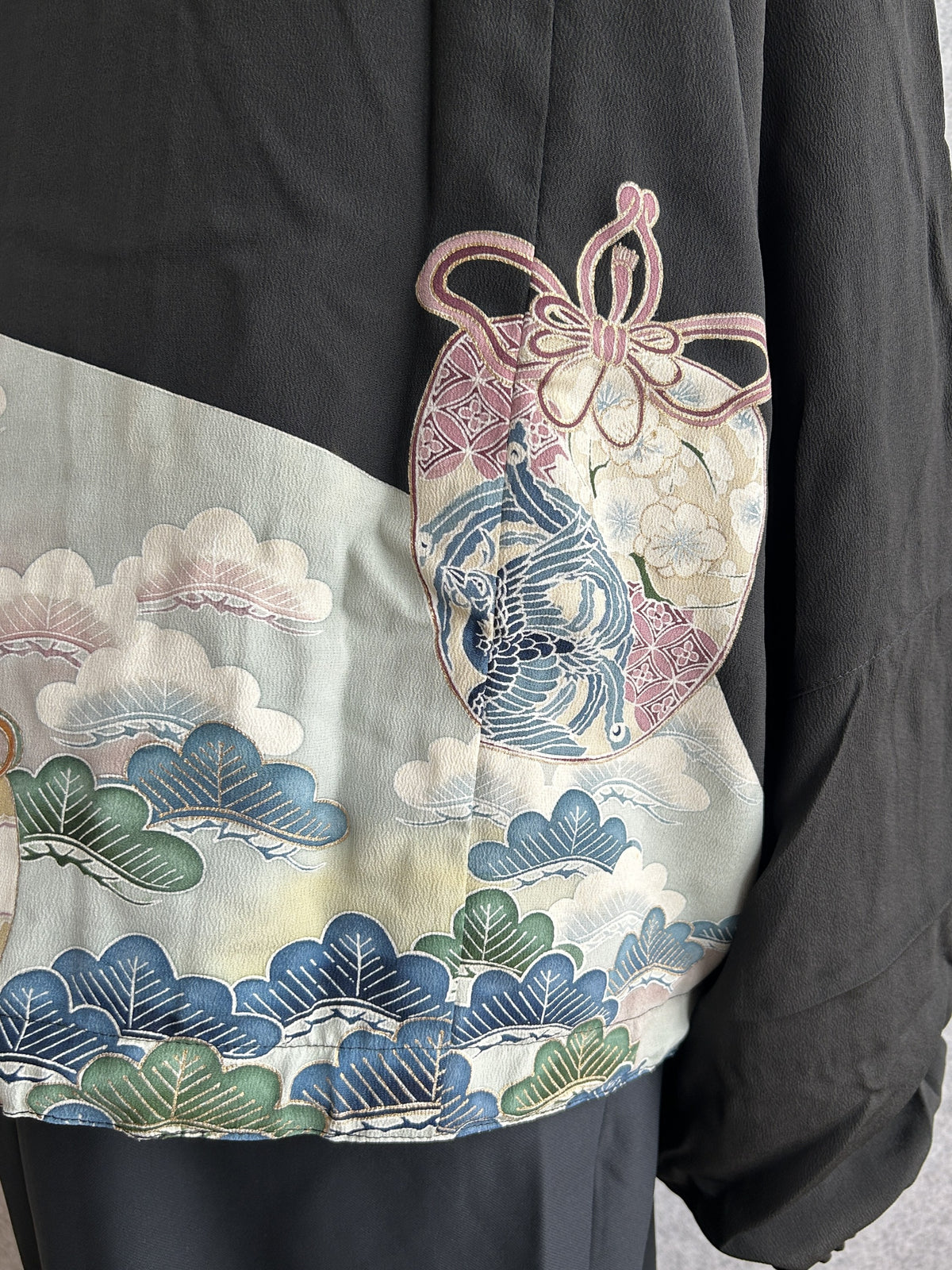 Black high collar kimono jacket, detail of pink tied pouch motif and clouds