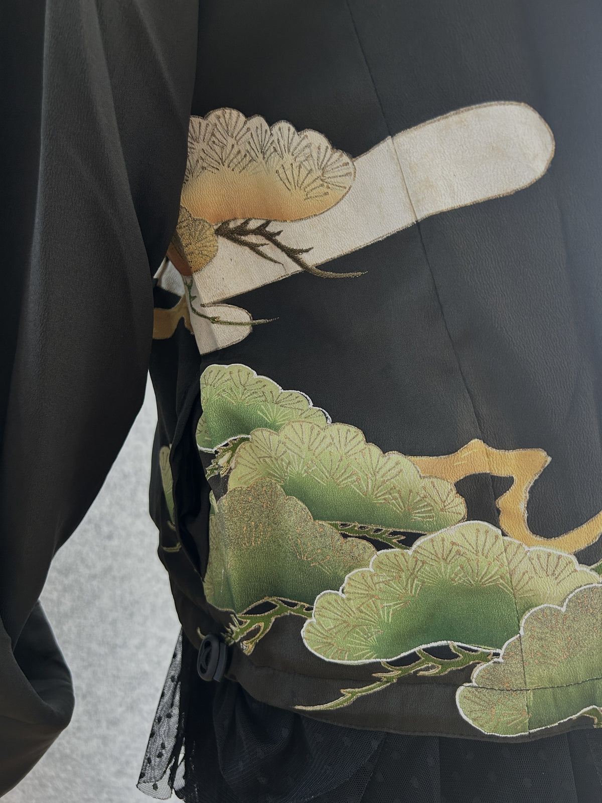 Black high collar kimono jacket with pine motifs, side detail of green pine motifs at the hem