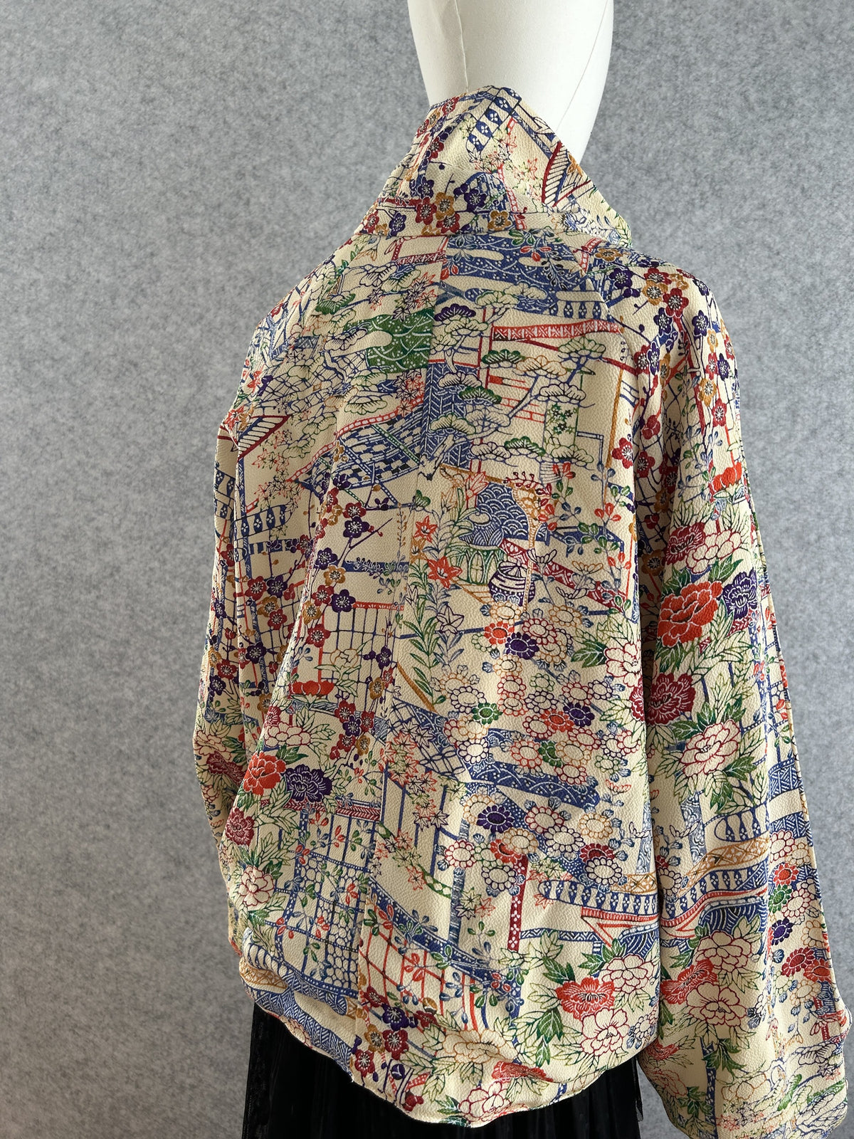 Cream high collar kimono jacket with colourful flowers, back view from the side