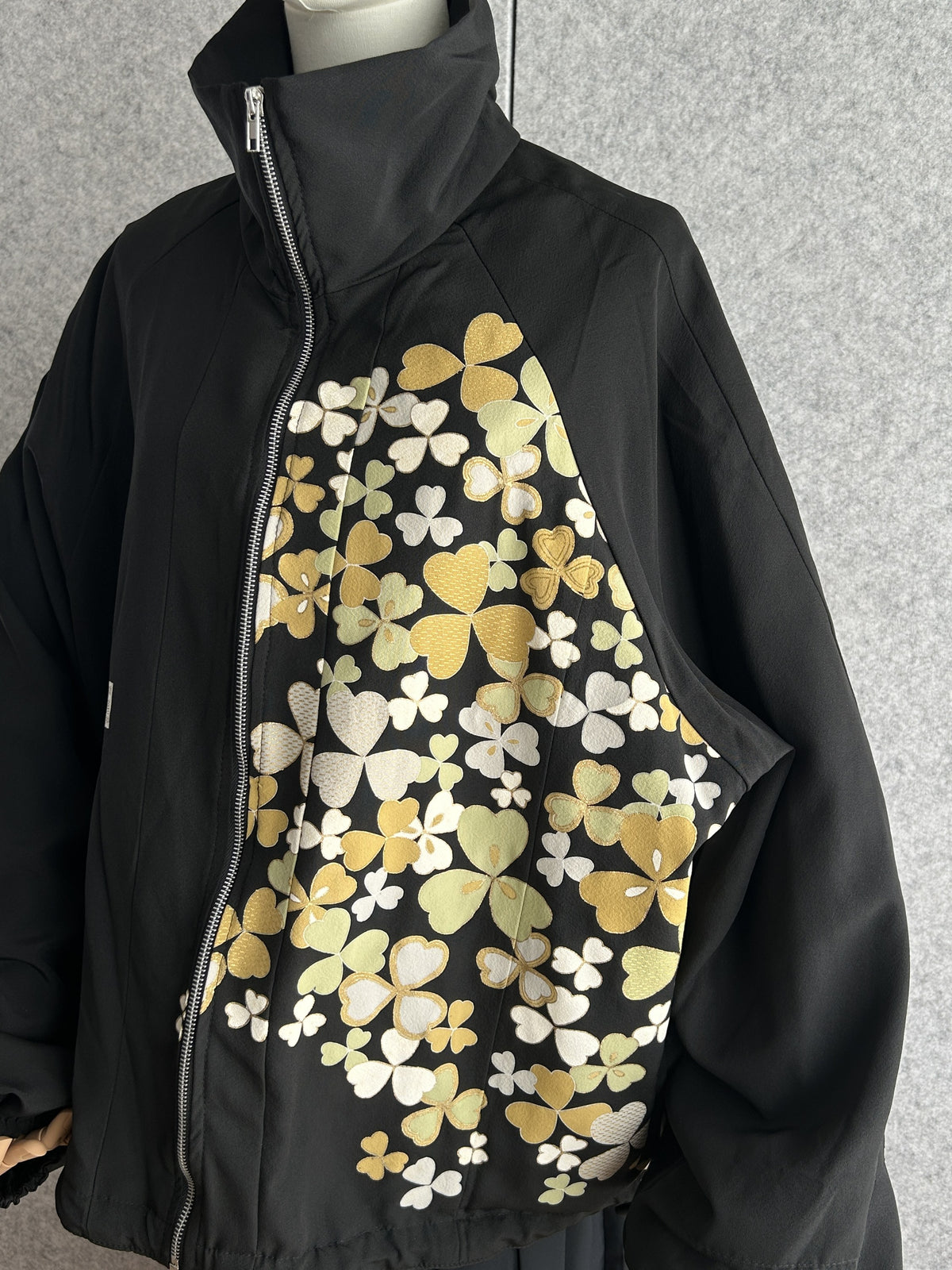 Black high collar kimono jacket with clover leaves, angled front view showing zipper and collar