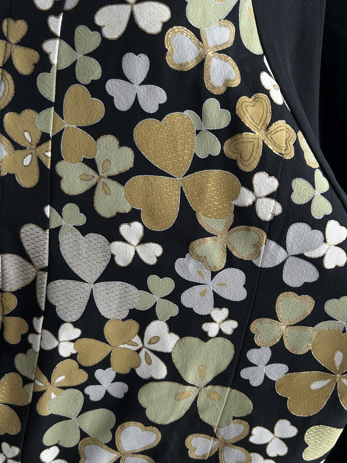 Black high collar kimono jacket with clover leaves, detail of the gold and green leaf shapes
