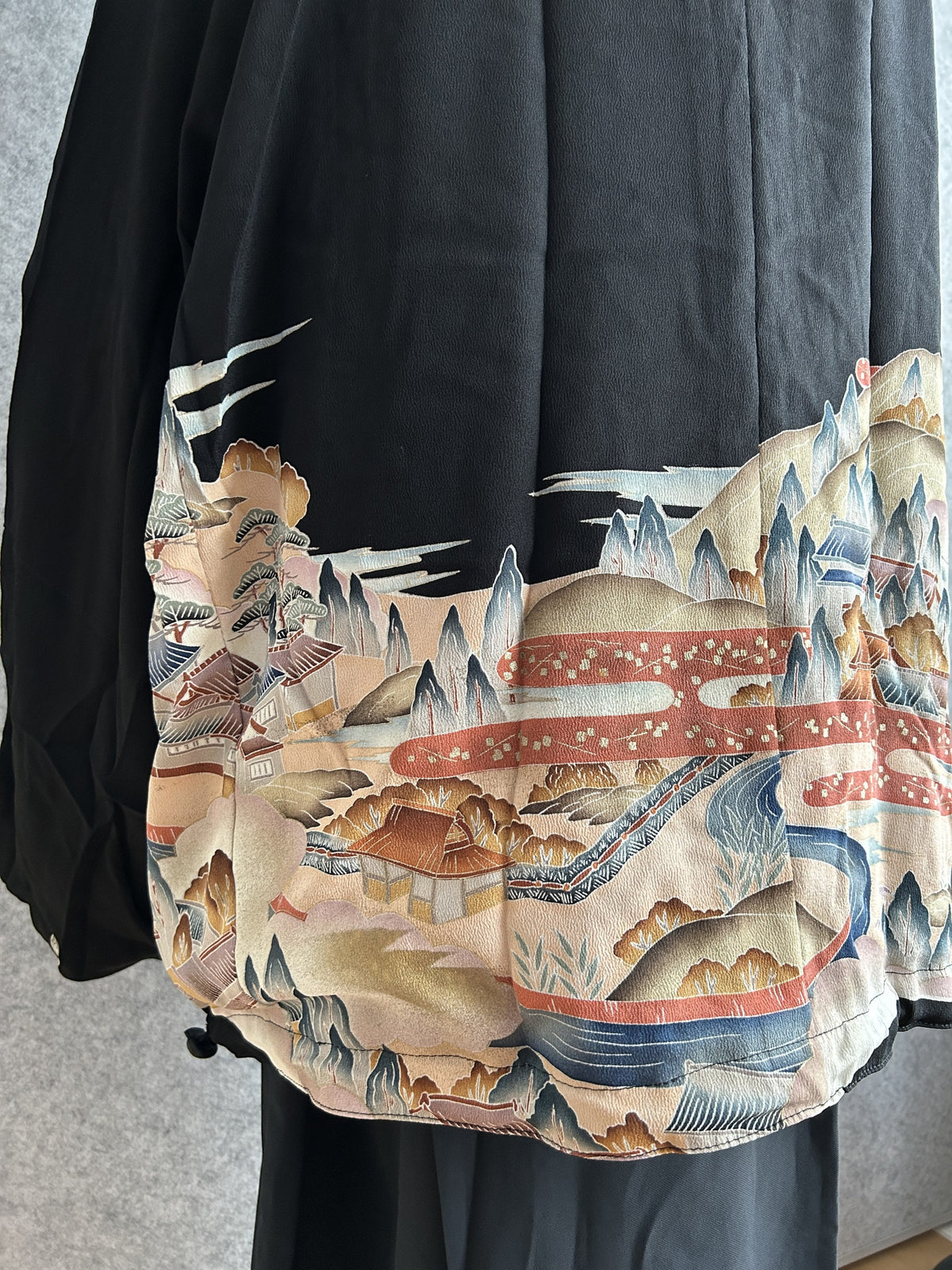 Black kimono jacket, detail of landscape scene on back hem, side angle