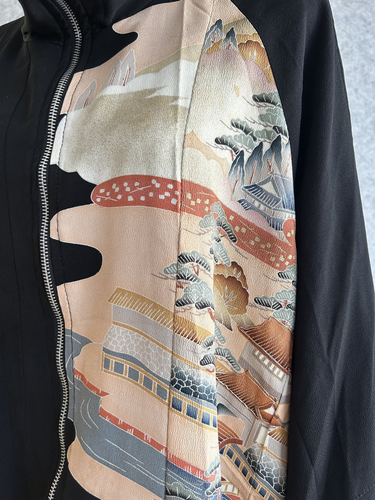 Black kimono jacket, detail of landscape panel with buildings beside the zipper