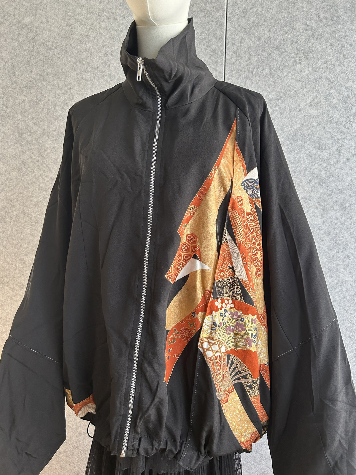 Black high collar kimono jacket with orange and gold panel, front view