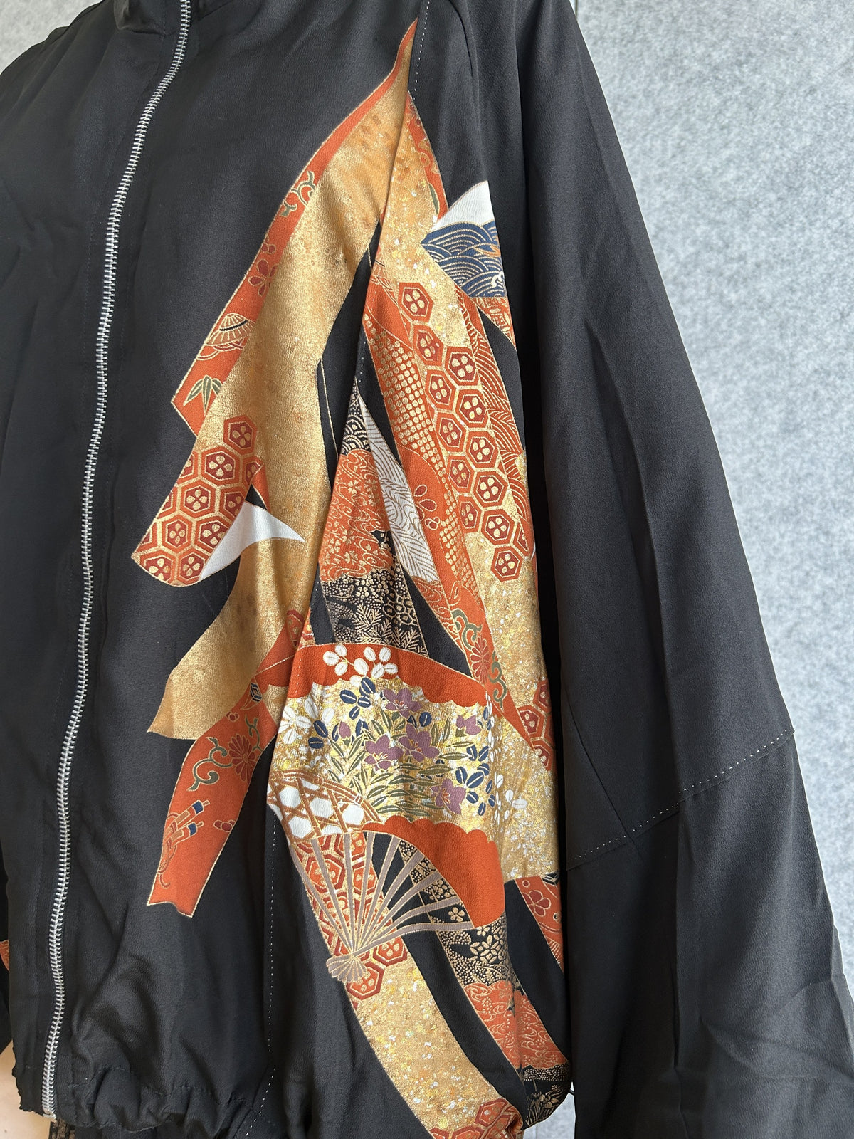 Black kimono jacket, close-up of orange and gold fan motifs on front