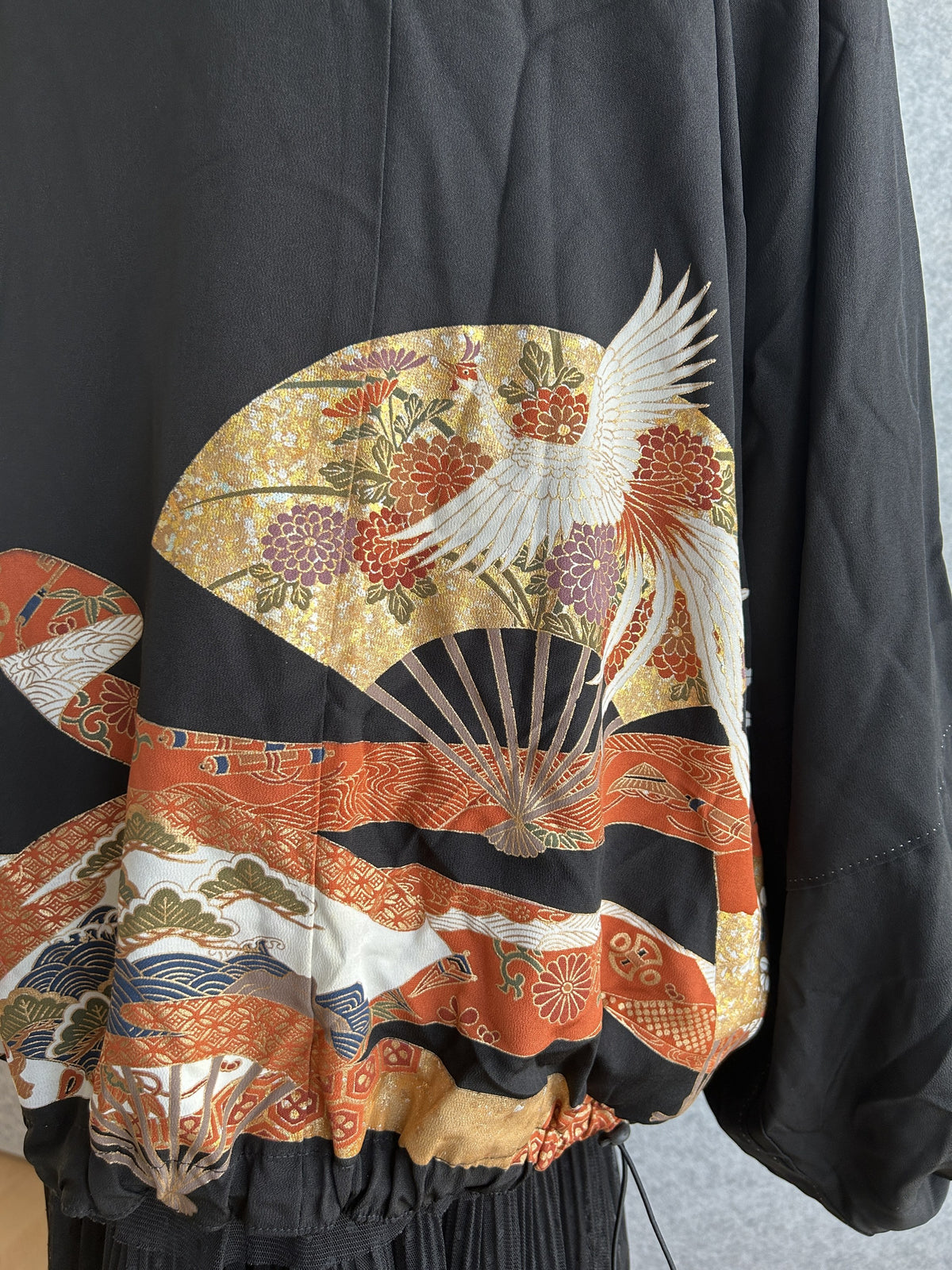 Black kimono jacket, close-up of gold fan with white crane on back