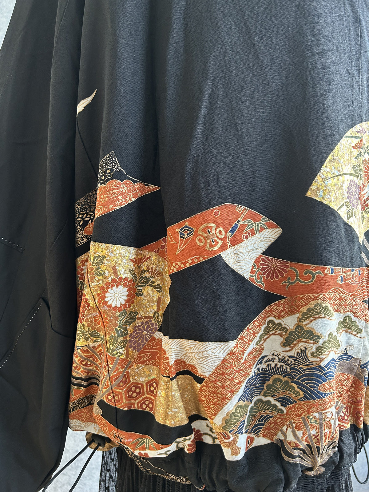 Black kimono jacket, detail of orange and gold motifs at back hem