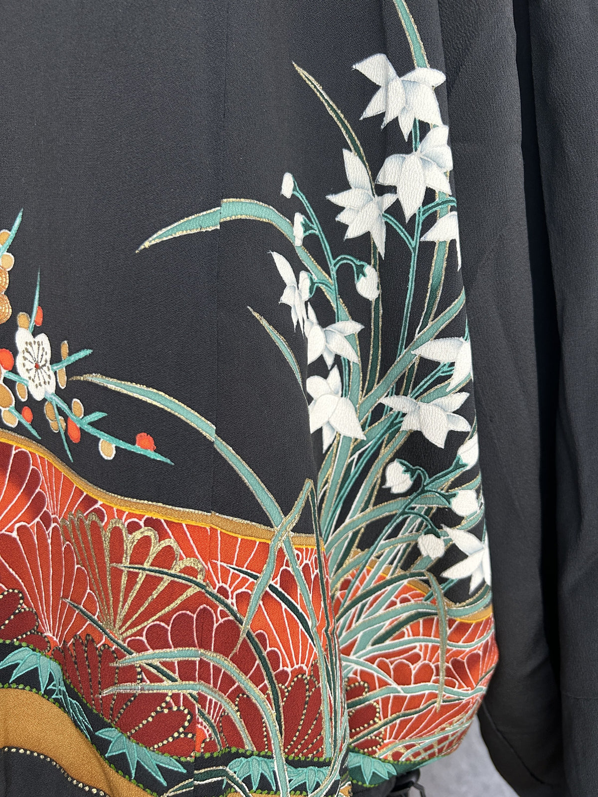 Black kimono jacket, close-up of white flowers with green leaves on back