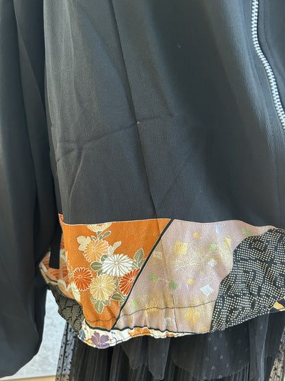 Black kimono jacket hem with orange floral band and zipper, detail
