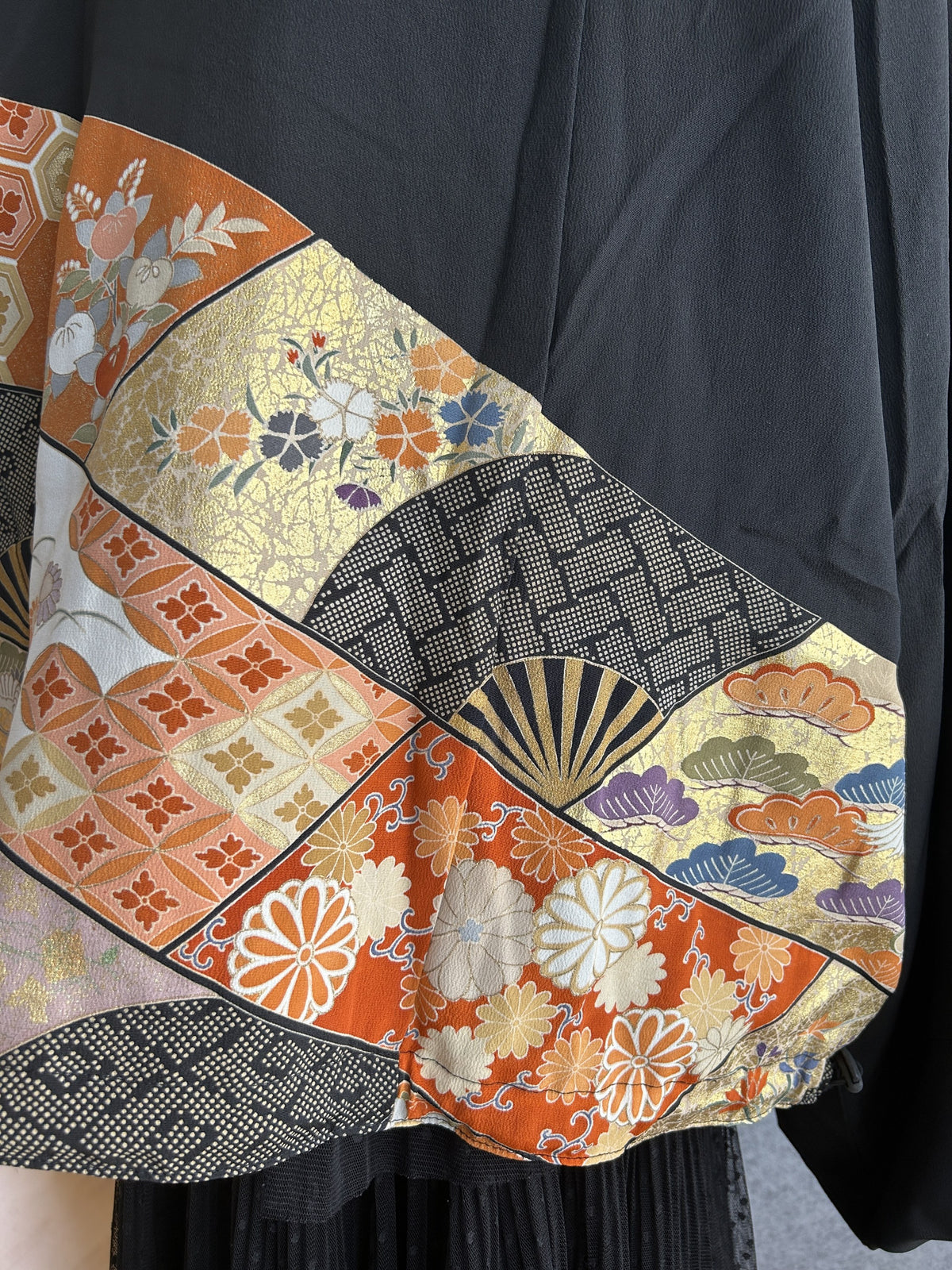 Black kimono jacket lower back with orange and gold patterned panel, detail
