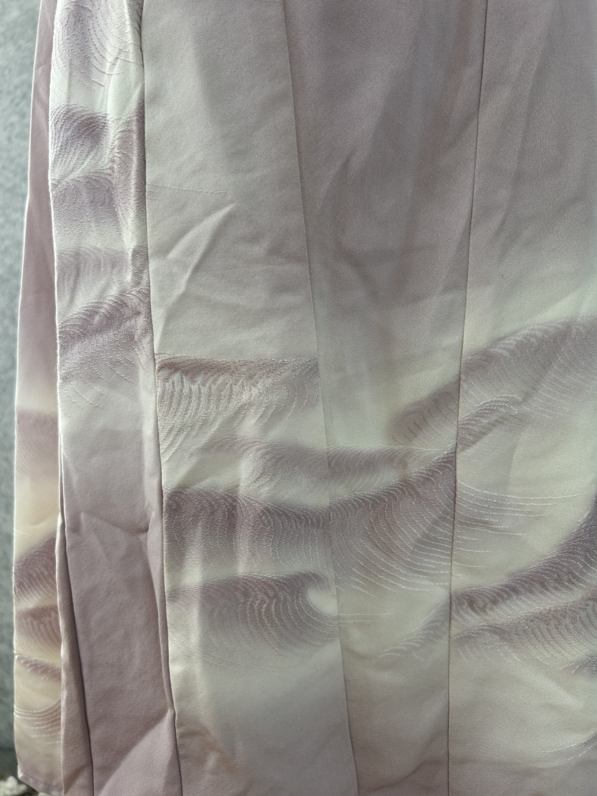 Detail of wave pattern along the panelled hem of the lilac dress