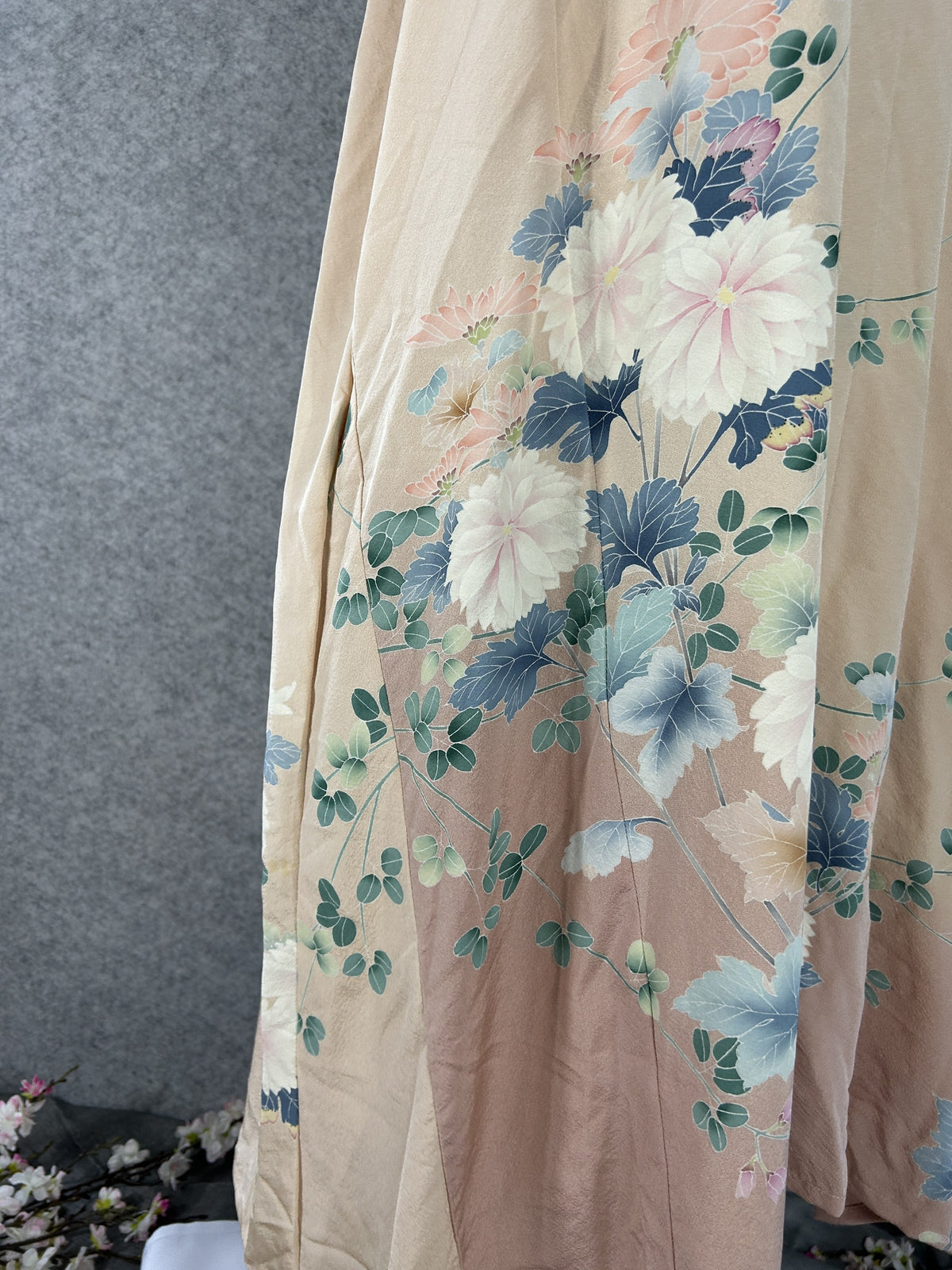 Detail of white and pink chrysanthemums with blue-grey leaves on peach silk