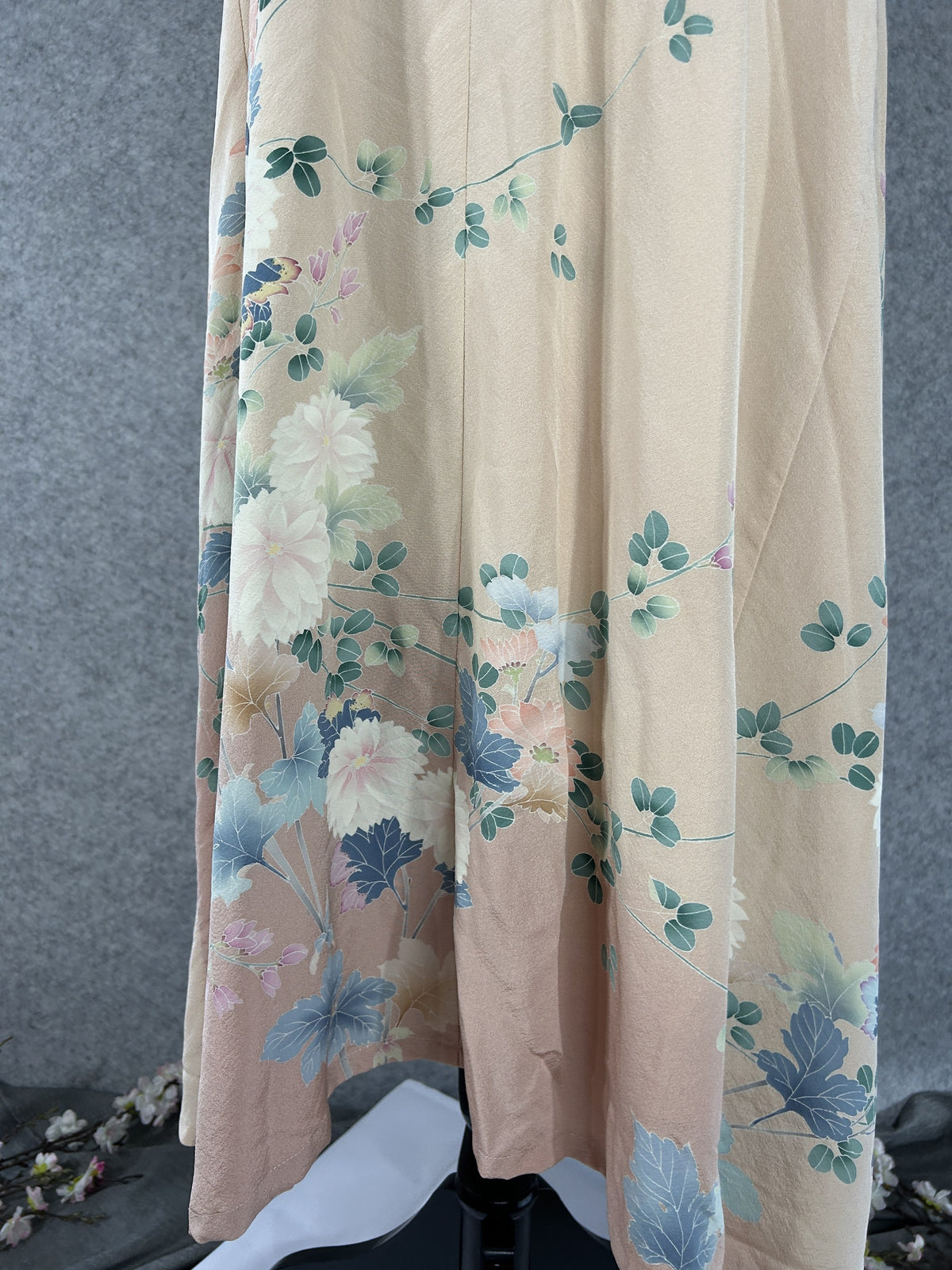 Painted chrysanthemums and green sprigs on the hem of a peach kimono dress