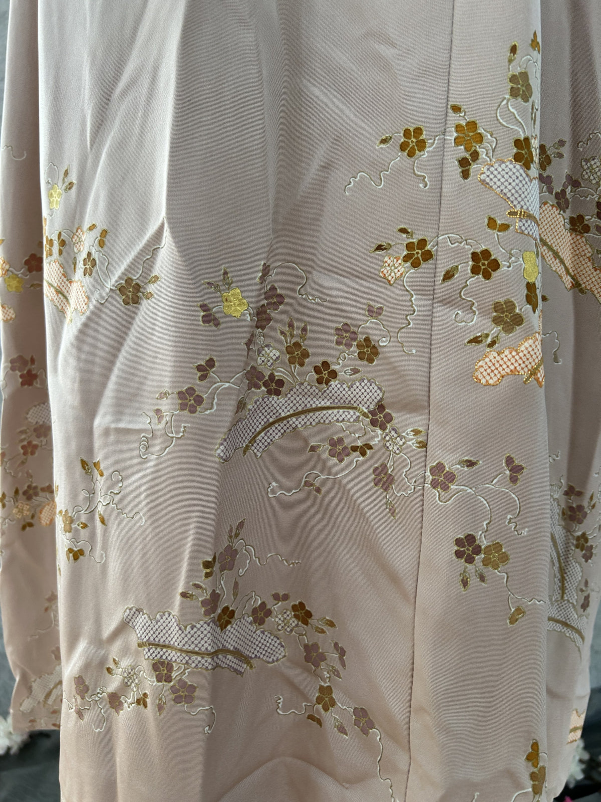 Detail of embroidered blossoms on vines along the beige dress hem
