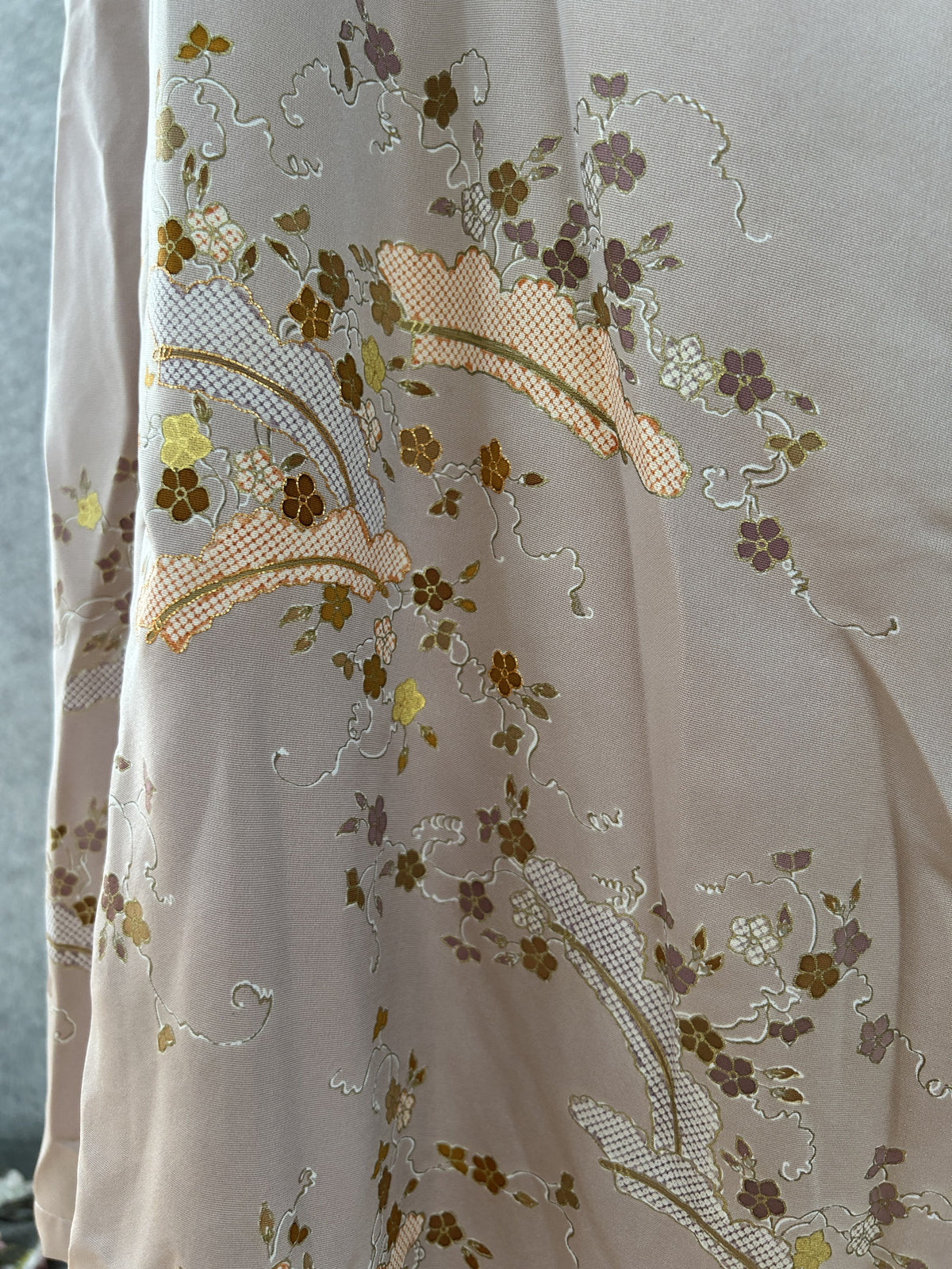 Close-up of embroidered blossoms and peach lattice fan on beige silk