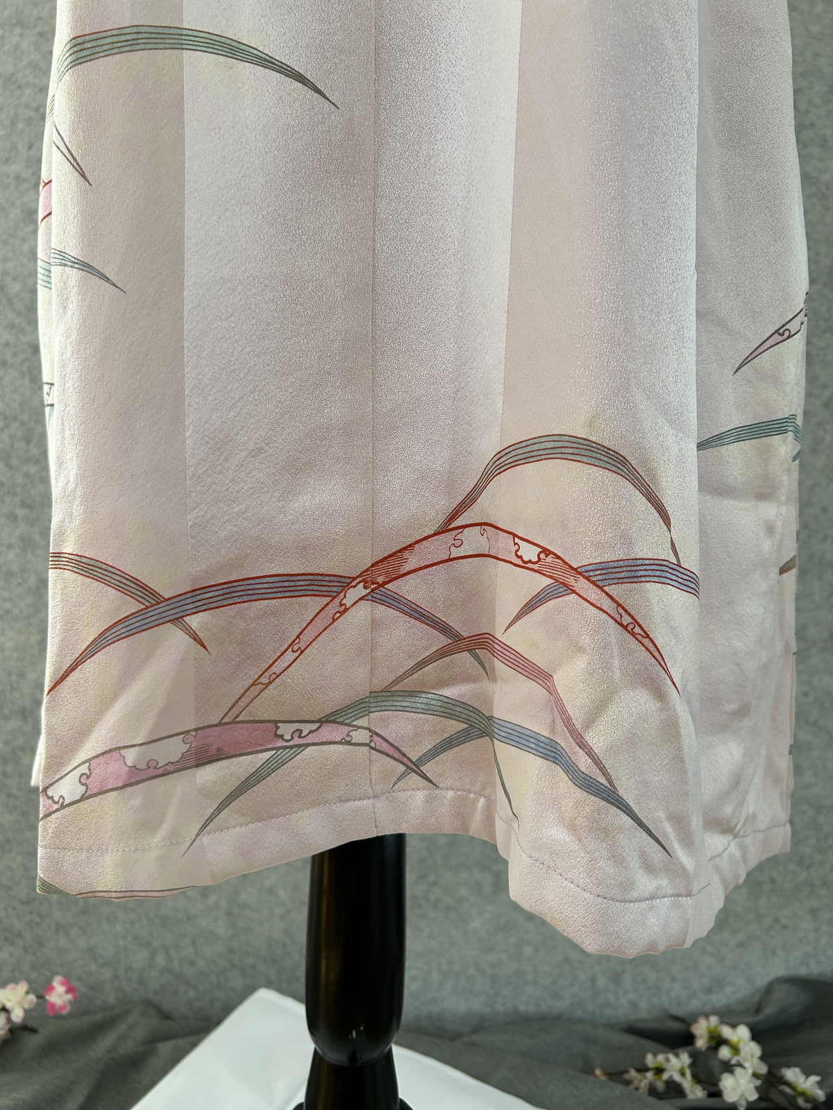 Detail of hem with grasses and cloud-patterned ribbons on pink silk