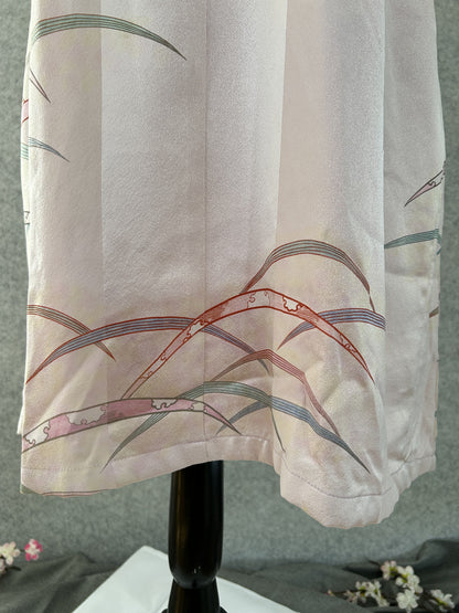 Detail of hem with grasses and cloud-patterned ribbons on pink silk