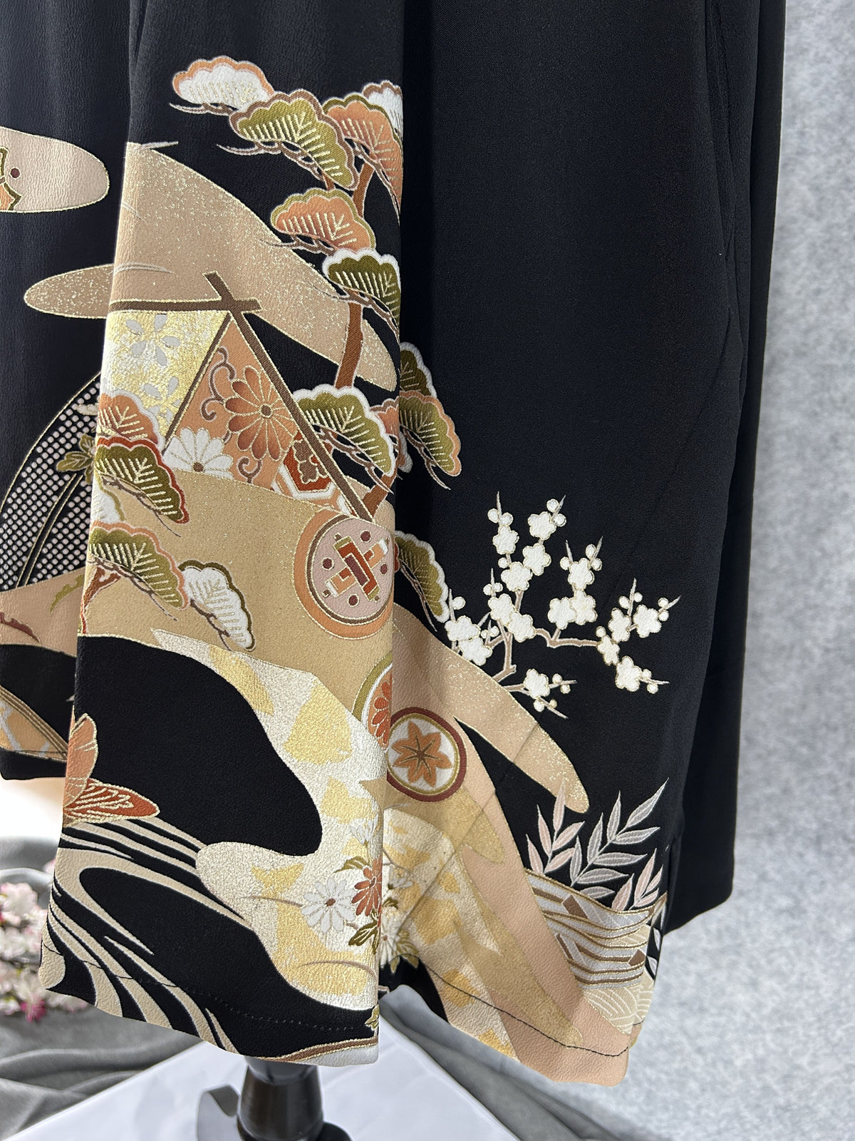 Close-up of pine branches, plum blossoms and gold clouds on black silk