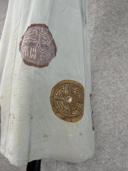 Detail of mauve and bronze round medallions with gold characters on sage silk