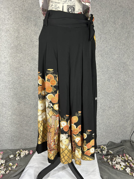Black upcycled tomesode kimono hakama pants with orange and gold chrysanthemums, front view