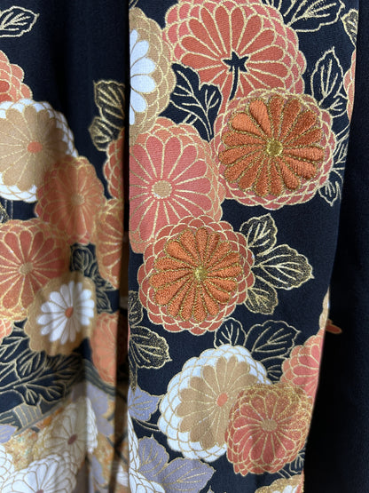 Black upcycled tomesode kimono hakama pants with orange and gold chrysanthemums, close-up of the embroidered chrysanthemums