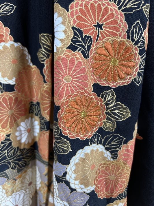 Black upcycled tomesode kimono hakama pants with orange and gold chrysanthemums, close-up of the embroidered chrysanthemums