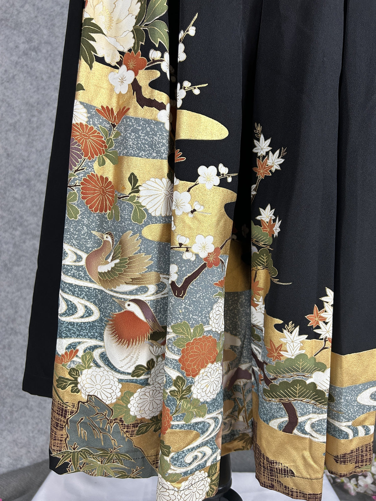 Black upcycled tomesode kimono hakama pants with mandarin ducks and peonies, close-up of the hem with ducks and plum blossoms