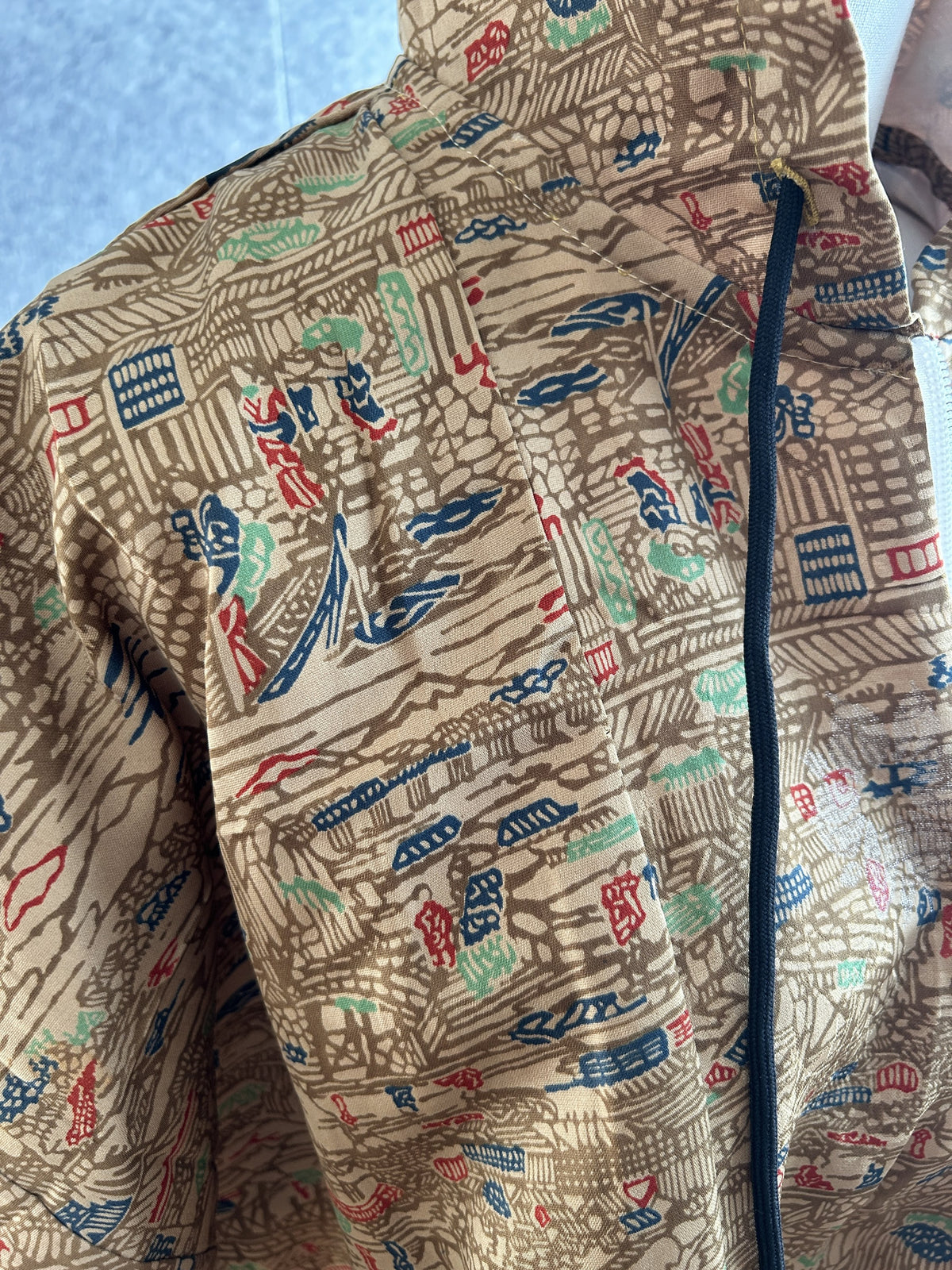 Beige poncho fabric with navy, red and green pattern, zipper detail