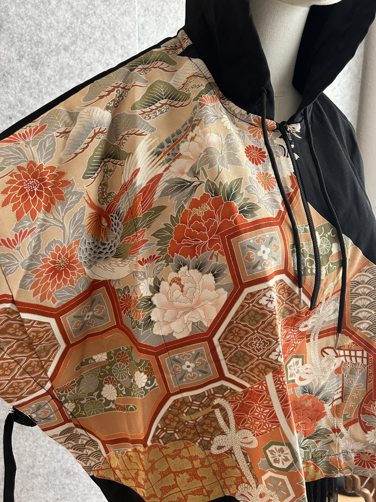 Black hooded kimono poncho, detail of bird, flowers and hexagon pattern