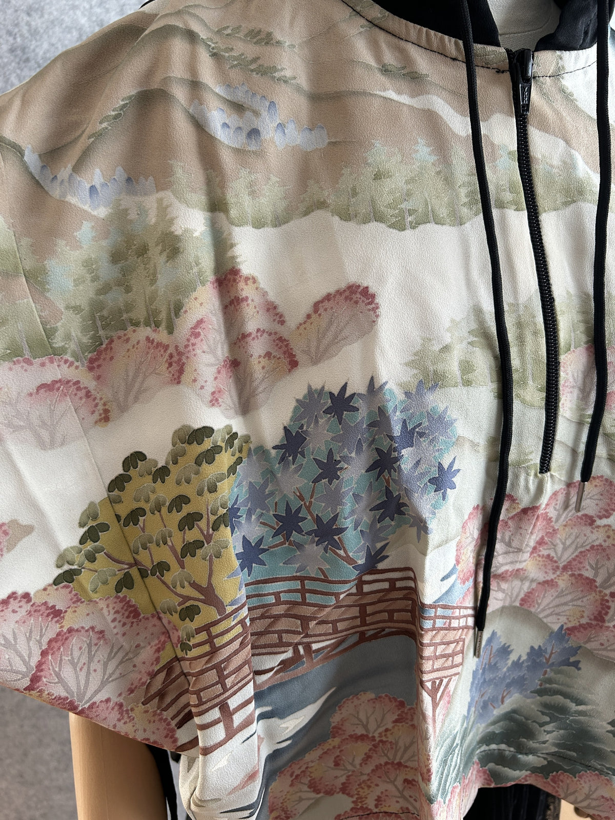 Black and cream hooded kimono poncho, detail of trees and wooden bridge