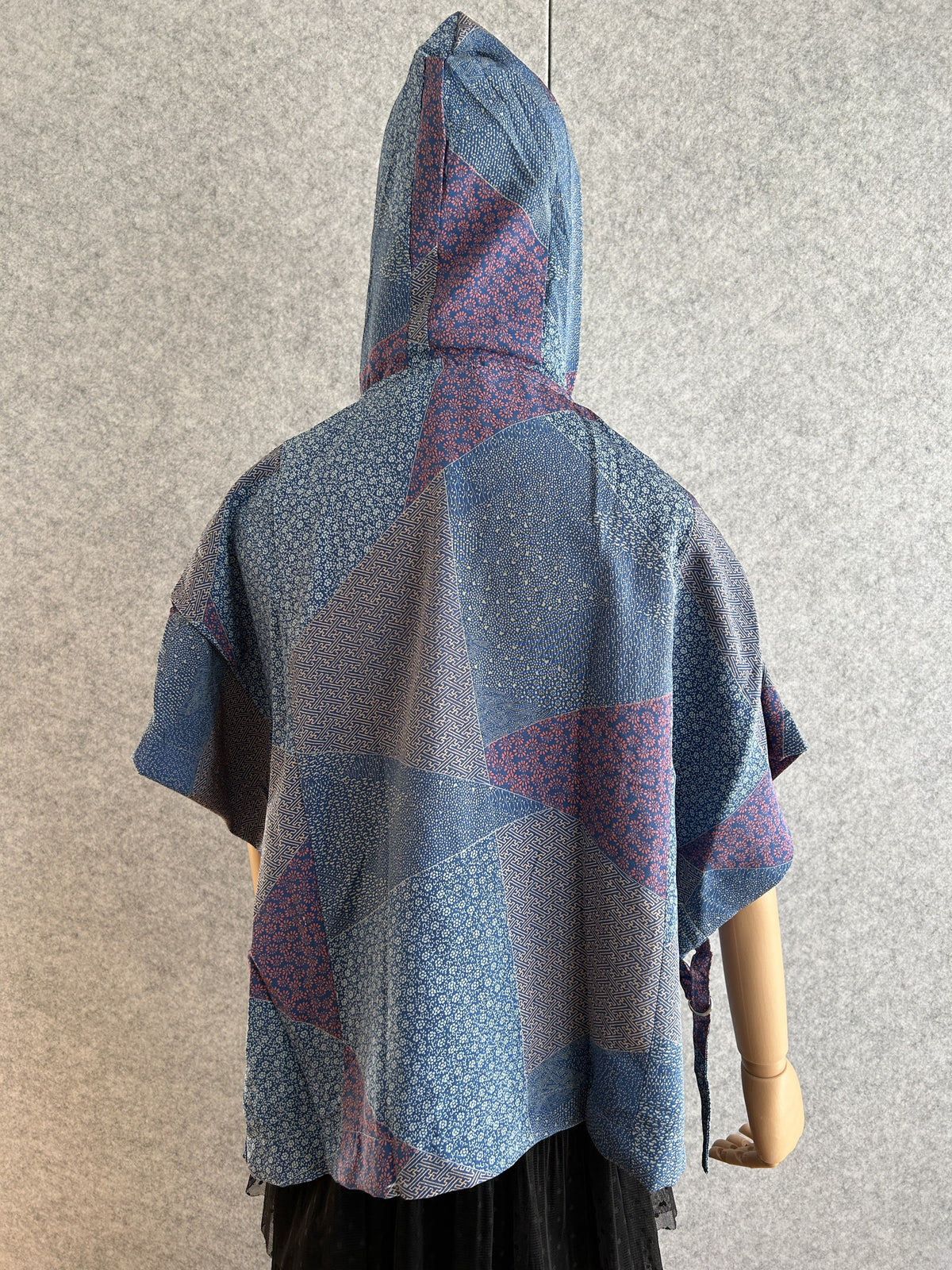 Blue hooded kimono poncho with patchwork of small patterns, back view