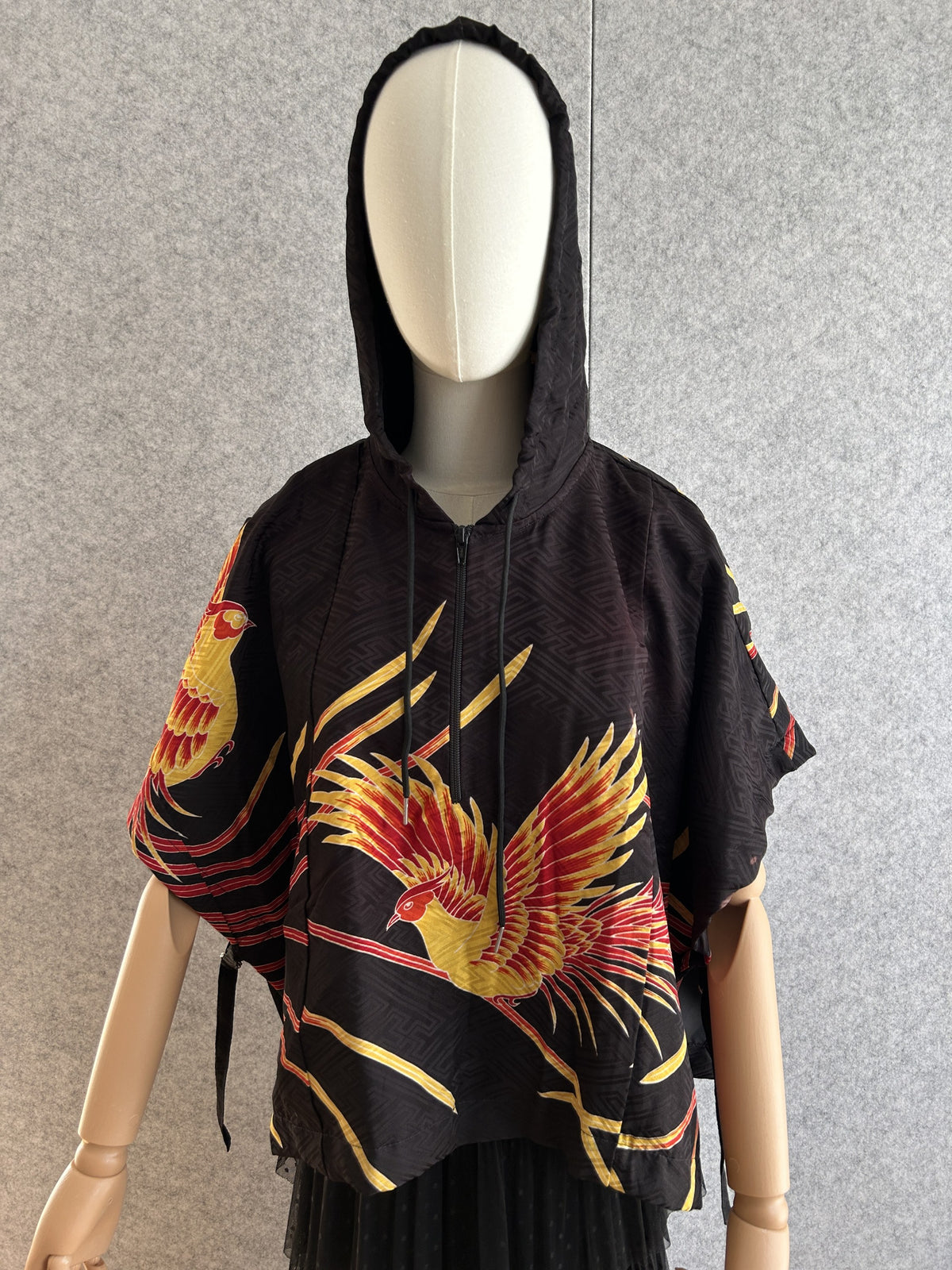 Black hooded kimono poncho with yellow and red bird motif, front view