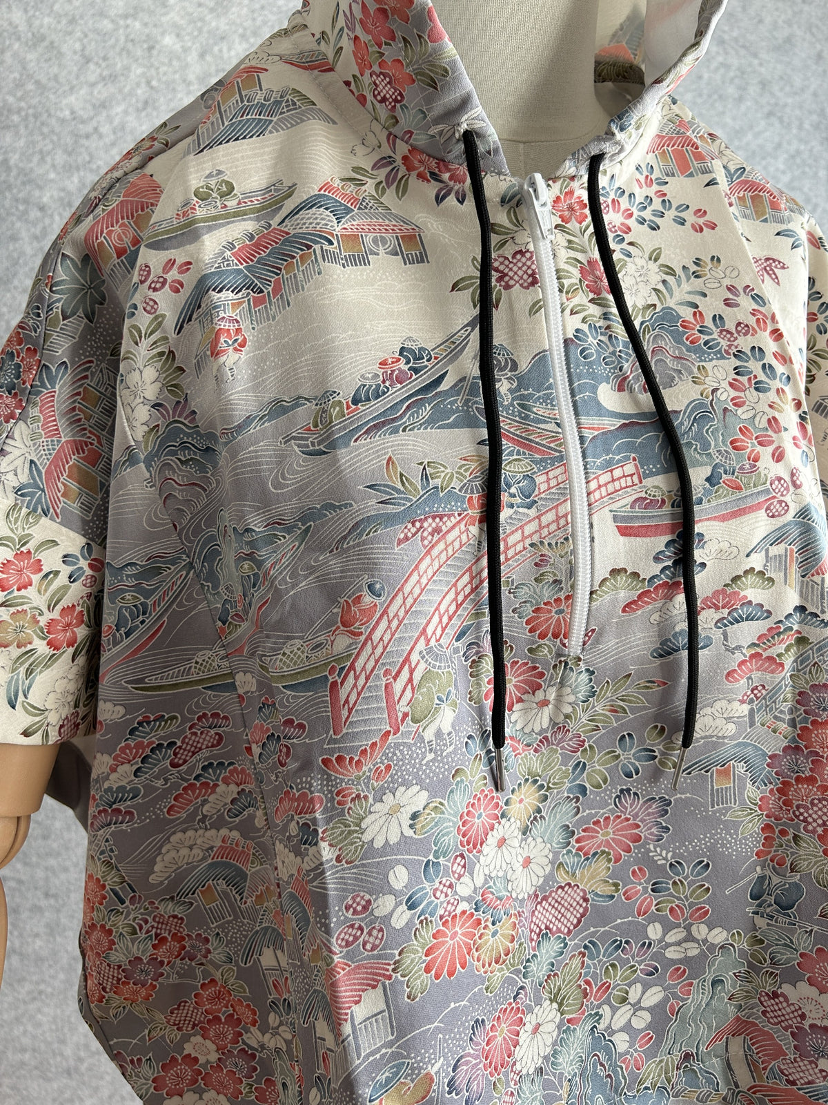 Cream hooded kimono poncho, detail of bridge, flowers and white zipper