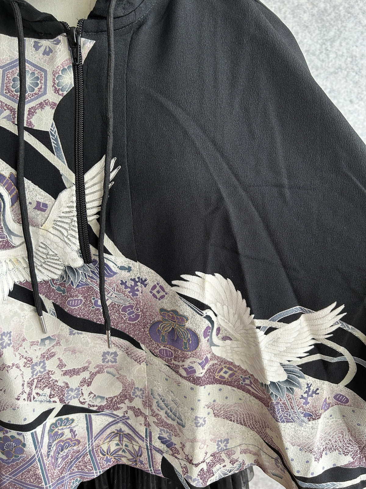 Black hooded kimono poncho, detail of crane, drawstrings and zipper