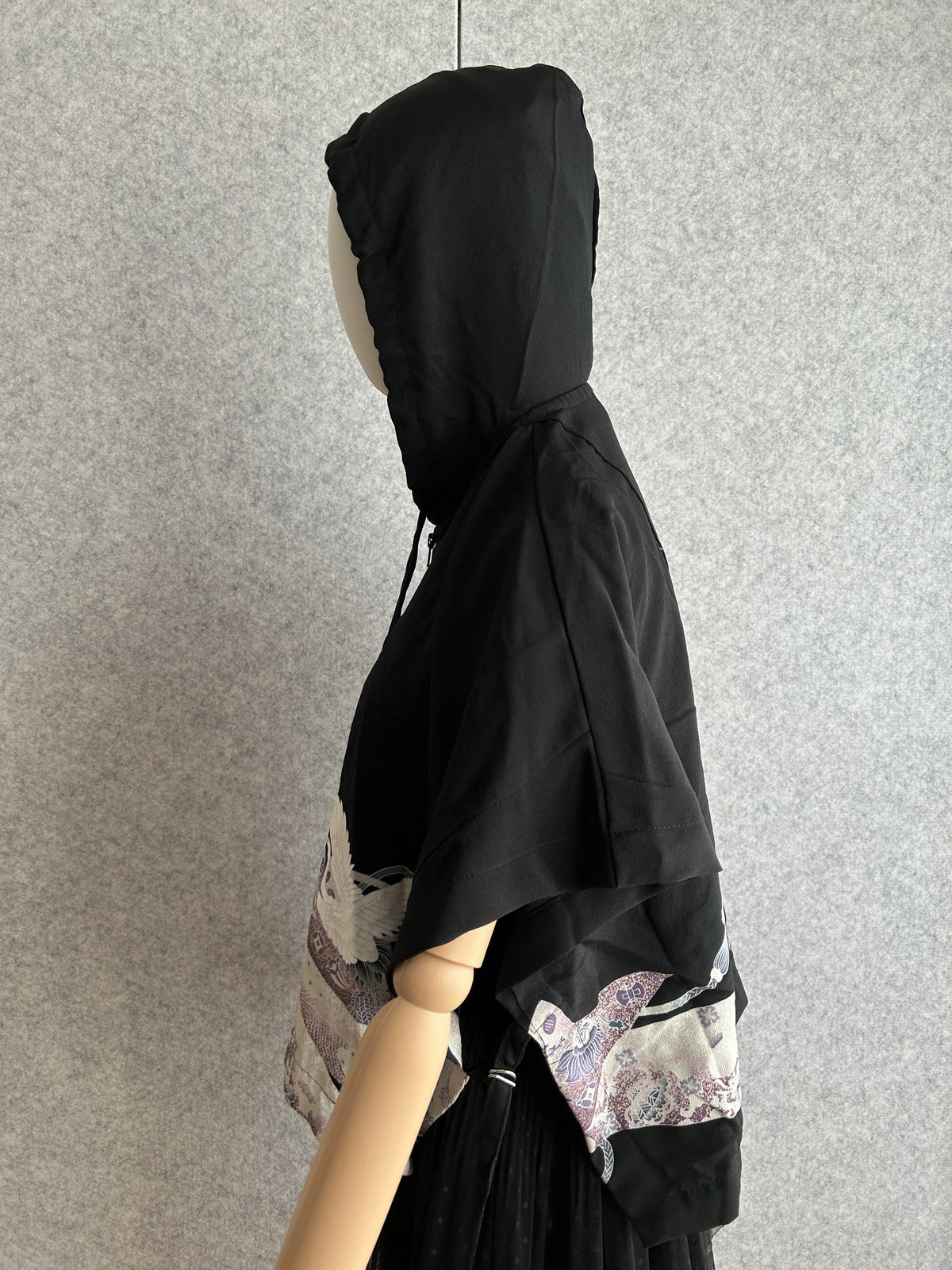 Black hooded kimono poncho with purple patterned hem, side view