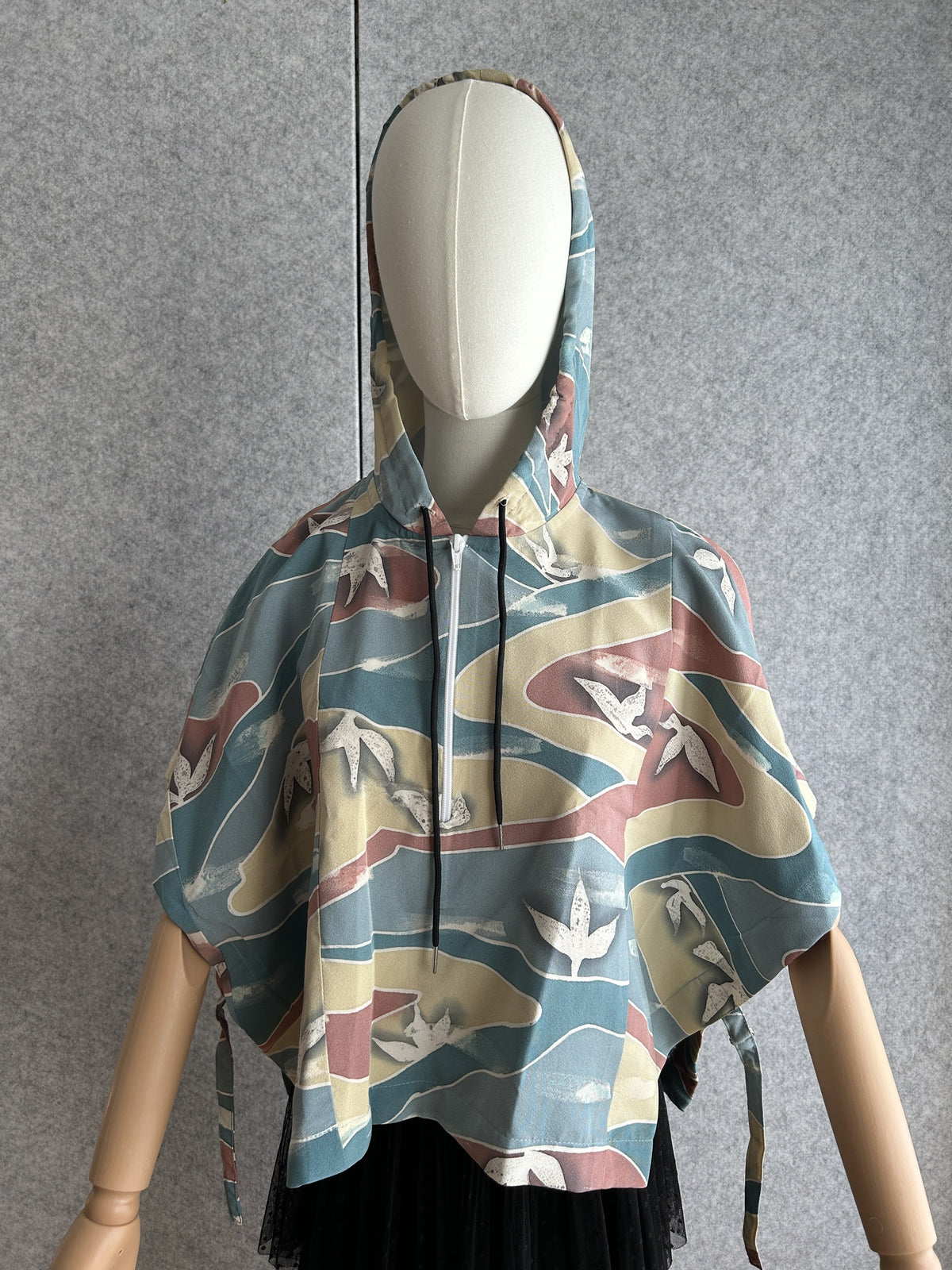 Teal blue hooded kimono poncho with yellow and red waves, front view